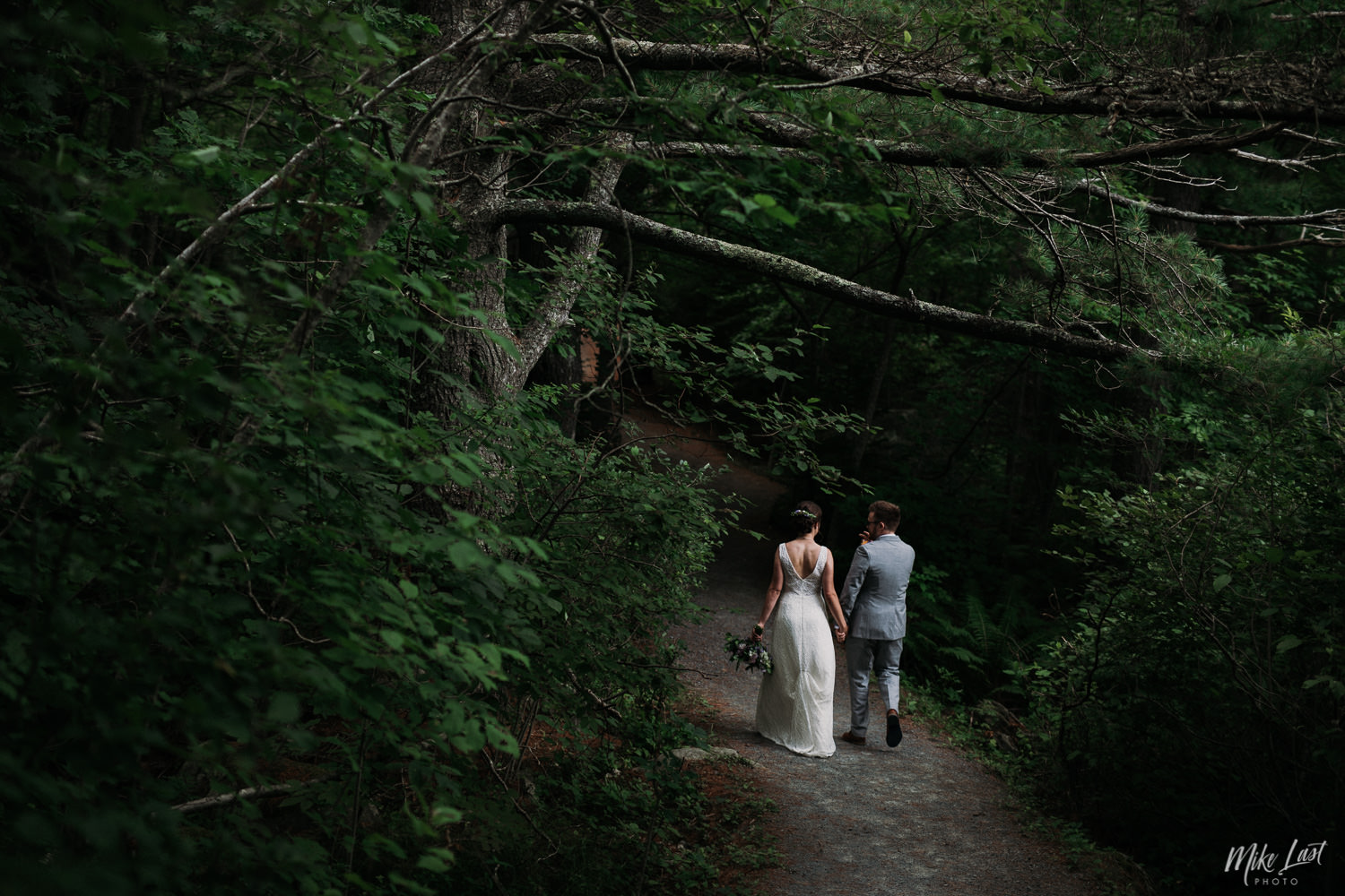Bride and groom walking through the forest at Pine Grove Park in Liverpool, Nova Scotia