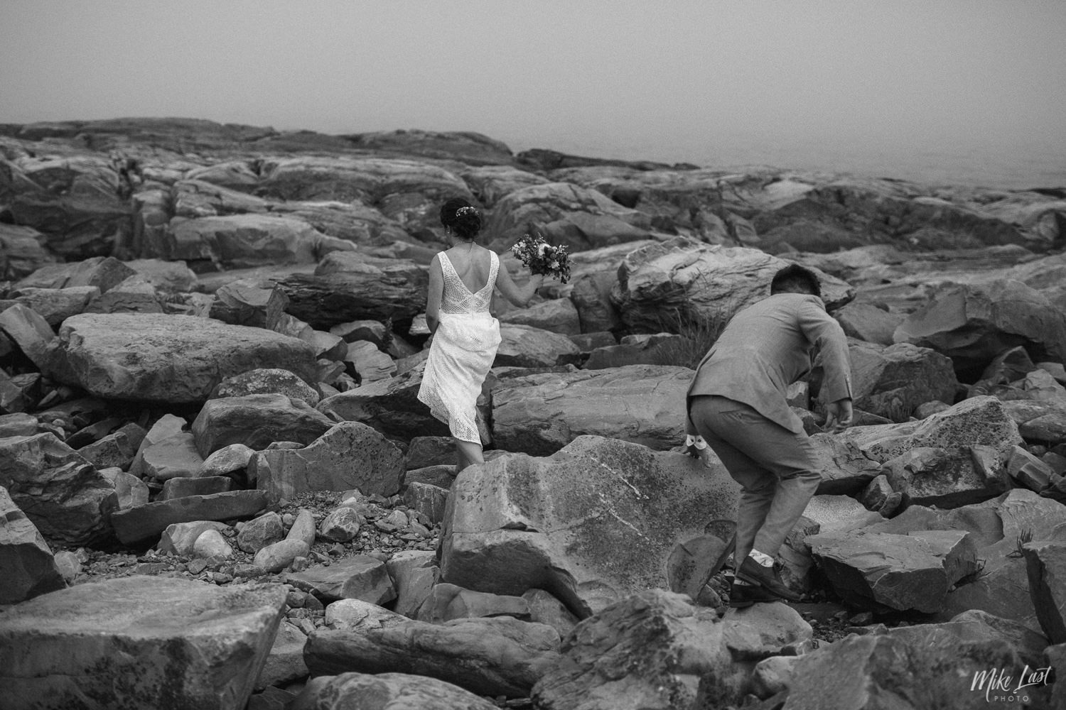 Bride and groom walking the rocks at Western Head Lighthouse in Nova Scotia.